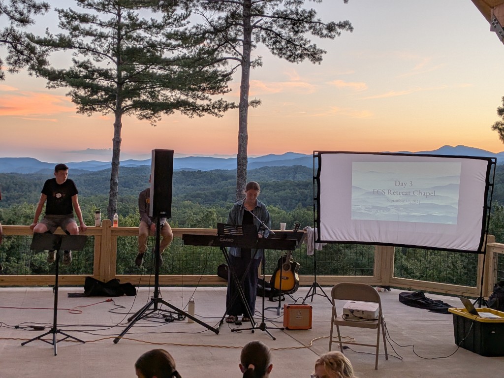 Students gathered for music and worship at an FCS retreat chapel overlooking the mountains at sunset